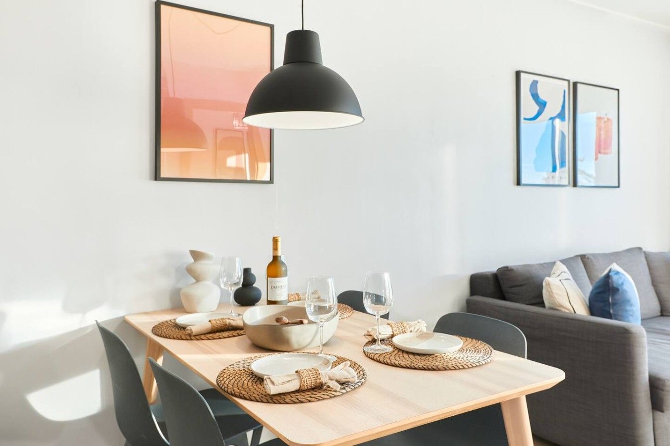 A dining area with a table set for two, a bottle of wine, and two glasses.
