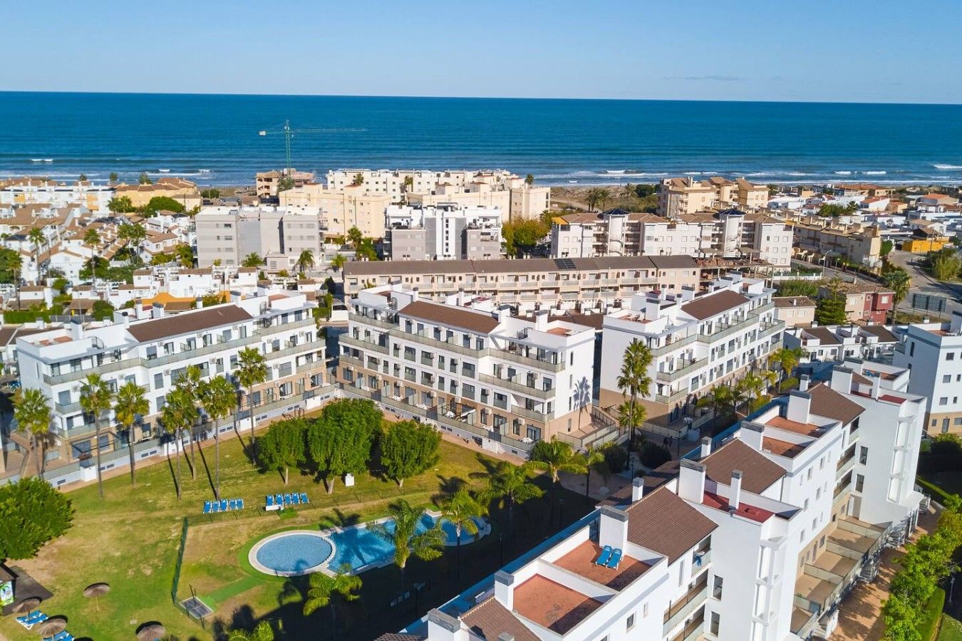 Un complexe hôtelier situé sur la côte, composé de plusieurs bâtiments, doté d’une piscine et offrant une vue sur la mer.
