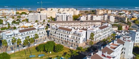 A coastal hotel complex with multiple buildings, a swimming pool, and a view of the sea.