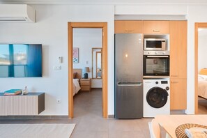 A compact kitchen with a refrigerator, microwave, oven, and washing machine. - Las Dunas 213 (Oliva)