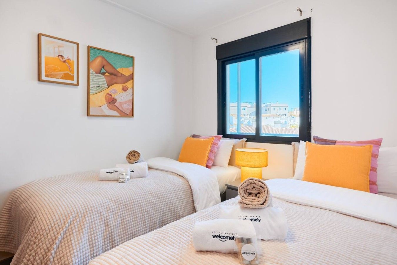 A hotel room with two beds, a window with a view, and artwork on the wall.