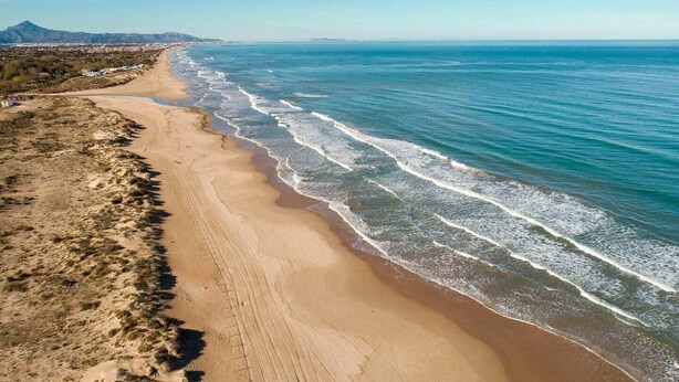 Eine Küstenlandschaft mit Sandstrand und Wellen.