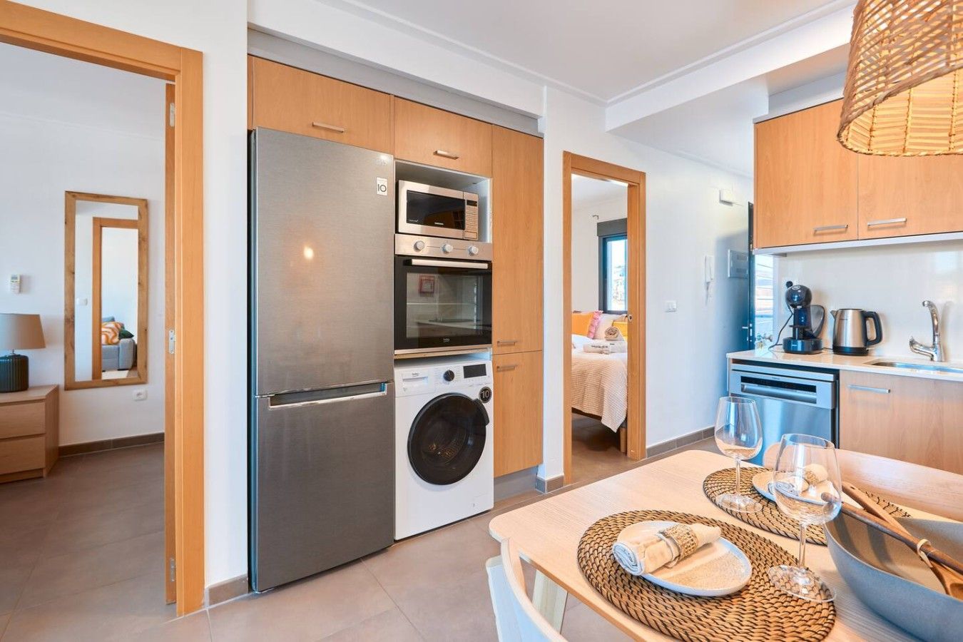 Una cocina moderna con electrodomésticos de acero inoxidable, armarios de madera y una zona de comedor con una mesa preparada para dos.