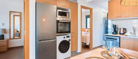 Una cocina moderna con electrodomésticos de acero inoxidable, armarios de madera y una zona de comedor con una mesa preparada para dos.