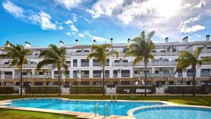 Ein Hotel mit Pool, Palmen und blauem Himmel.