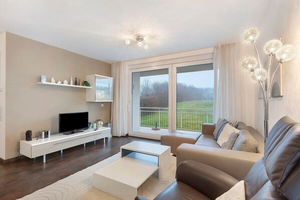 A modern living room with a flat-screen TV, a white console table, a sofa, and a coffee table.