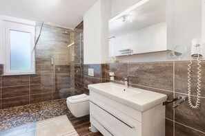 A modern bathroom with a shower, toilet, and sink.