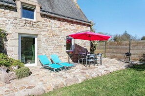 Una casa in pietra con patio, posti a sedere all'aperto e barbecue.