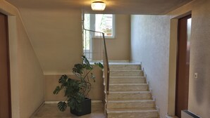 Eine Treppe mit Handlauf, einem Blumentopf und einem Fenster mit Blick ins Freie.