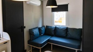 A room with a dark-colored sofa, two pendant lights, an air conditioning unit, and a window with a view. - 6-persons Holiday Home in Coma-ruga (El Vendrell)