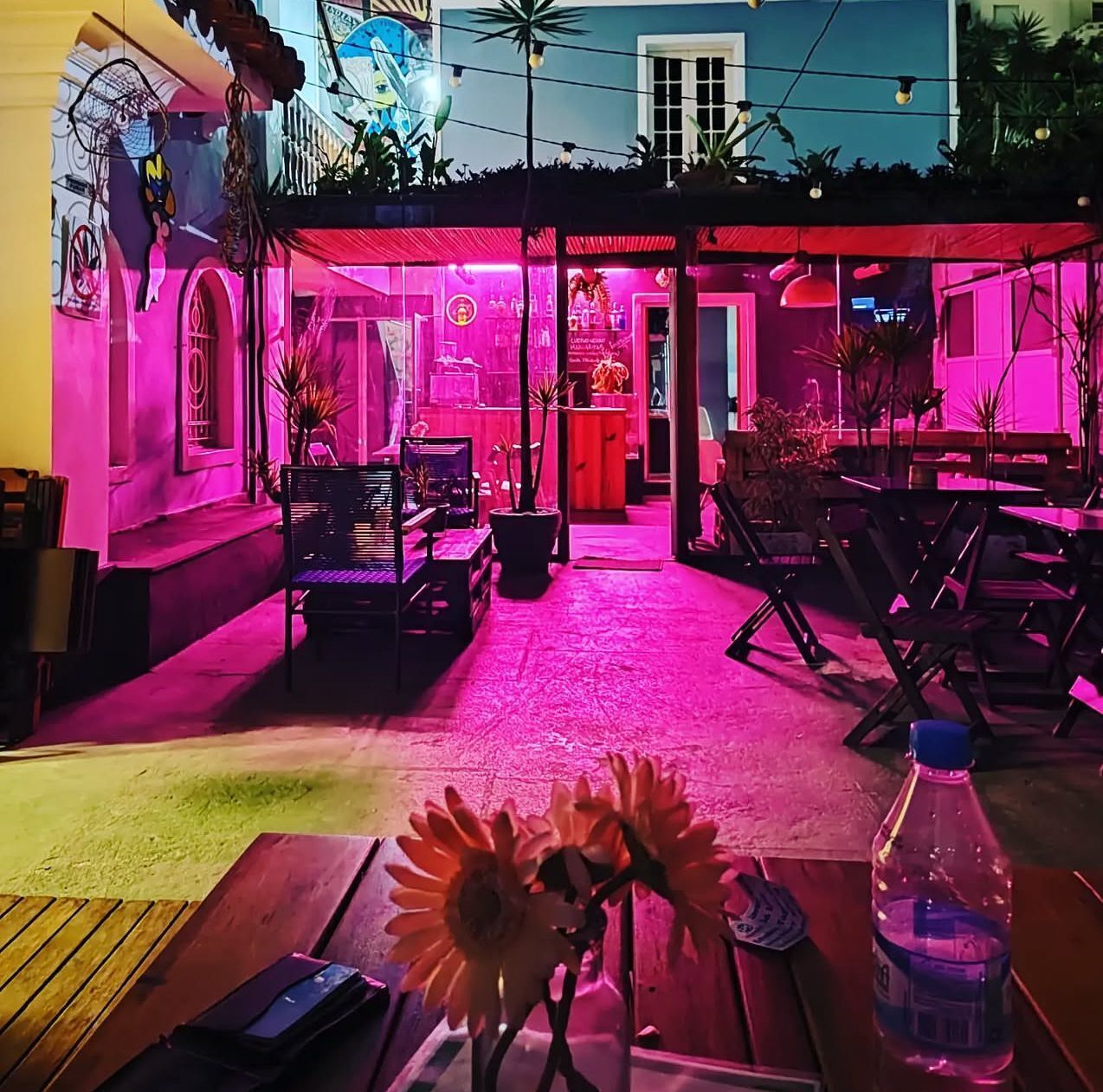 Un espace extérieur aménagé en terrasse, avec des sièges et des tables, éclairé par un éclairage rose.