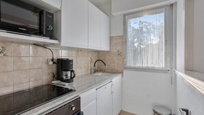 A compact kitchen with a microwave, coffee maker, and a window with a view of trees. - Apartment 'Estivales 2' with Private Terrace and Garden (Saint-Raphaël)