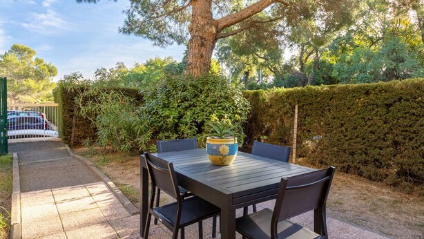 An outdoor patio with a table and chairs, surrounded by greenery and a large tree. - Apartment 'Estivales 2' with Private Terrace and Garden (Saint-Raphaël)