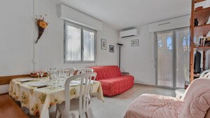 A dining area with a table set for four, a red sofa, and a pink chair. - Apartment 'Estivales 2' with Private Terrace and Garden (Saint-Raphaël)