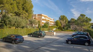 A parking lot with several cars, a building with multiple floors, and surrounding greenery. - Apartment 'Estivales 2' with Private Terrace and Garden (Saint-Raphaël)