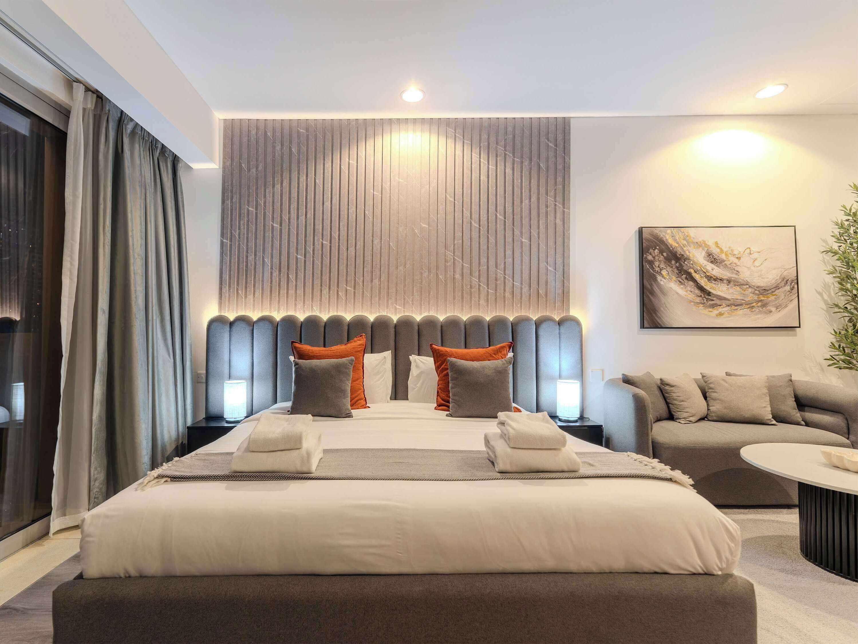 Une chambre d’hôtel moderne avec un grand lit, un canapé et une petite table.