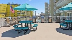 Terraza en la azotea con mobiliario exterior y sombrillas, con vistas a la ciudad.