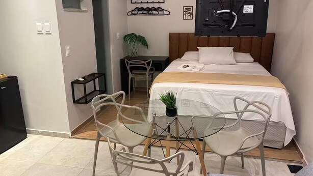 A compact hotel room with a bed, a desk, and a chair. - Modern studio in the city center | Kitchen and AC (Petrolina)