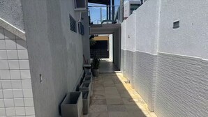A narrow alleyway with tiled walls and a tiled floor, leading to a building entrance. - Modern studio in the city center | Kitchen and AC (Petrolina)
