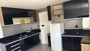 Eine moderne Küche mit schwarzen Schränken, einem weißen Kühlschrank und einer schwarzen Arbeitsplatte.