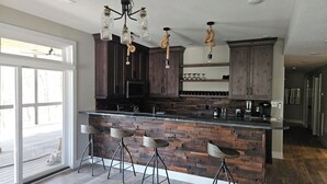 Una cocina moderna con barra, armarios de madera y una lámpara original.