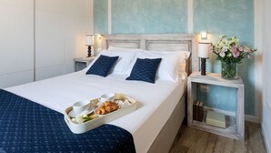 A neatly made bed with pillows, a tray of breakfast, and a vase of flowers on a bedside table. - Strozzi Terrace View (Firenze)