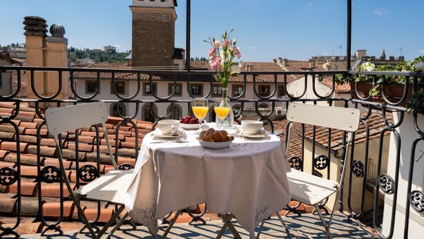 A balcony with a table set for breakfast, including croissants, fruit, and orange juice. - Strozzi Terrace View (Firenze)