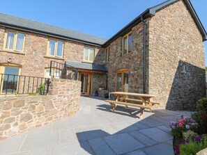 A stone building with a wooden bench and a sign reading "Cottage." - Grange Cottage (Crediton)