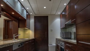 A modern kitchen with wooden cabinets, stainless steel appliances, and a tiled floor. - Downtown 1BHK apartment with City view (Dubai)