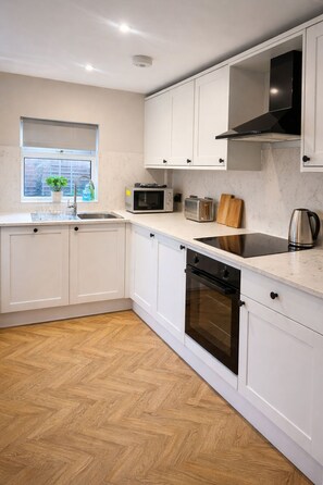 A modern kitchen with white cabinetry, a microwave, toaster, and a dishwasher. - Spacious and New! 3 bed Listing in Manchester. Board games, Smart TV and Guitar! (Manchester)