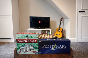 A Monopoly board game, a Pictionary box, a guitar, and a television in a room. - Spacious and New! 3 bed Listing in Manchester. Board games, Smart TV and Guitar! (Manchester)