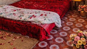A room with a bed, two nightstands, a wall-mounted light fixture, and a patterned floor. - A Rustic Bamboo-Themed Farmhouse in Jaipur with Swimming Pool & Jacuzzi Escape (Rawlot Nagar)
