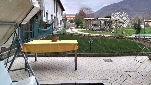 Eine Terrasse mit einem gelben Tisch, einem Metallstuhl und einer grünen Plane.