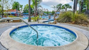 Un jacuzzi rodeado de palmeras y un área de piscina con sillas de descanso.