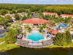 A resort with a central swimming pool, multiple buildings, and a surrounding natural landscape. - 25% Off Cozy Villa at Terre Verde! (Kissimmee)
