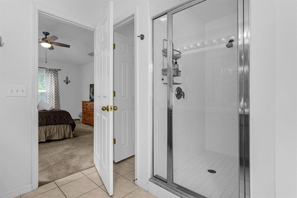 A bathroom with a glass-enclosed shower, a white toilet, and a white sink.