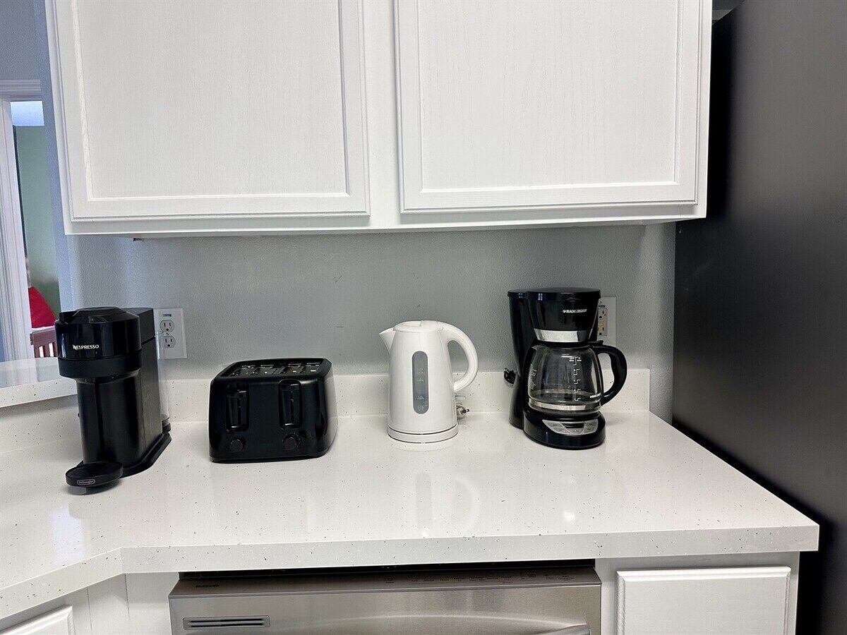 A kitchen counter with a coffee maker, toaster, and kettle.