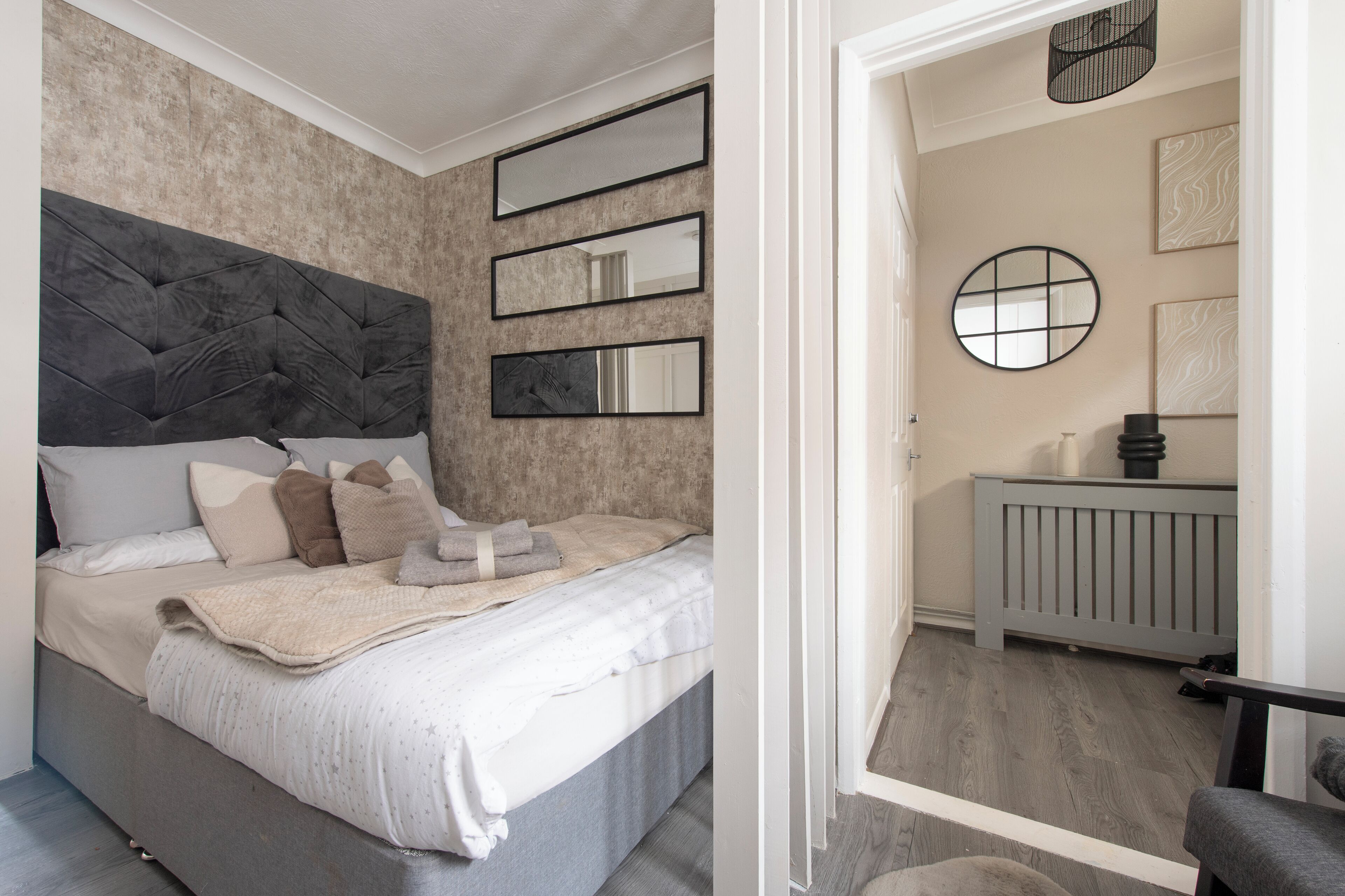 A bedroom with a bed, bedside tables, and a wall-mounted mirror.