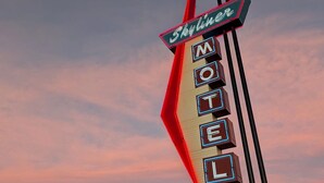 A motel sign with neon lights against a sunset sky. - Skyliner Motel (Stroud)