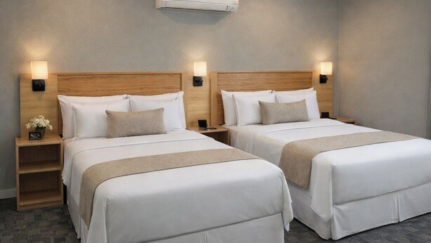 A hotel room with two beds, wooden headboards, bedside tables with lamps, and an air conditioning unit on the wall. - Skyliner Motel (Stroud)