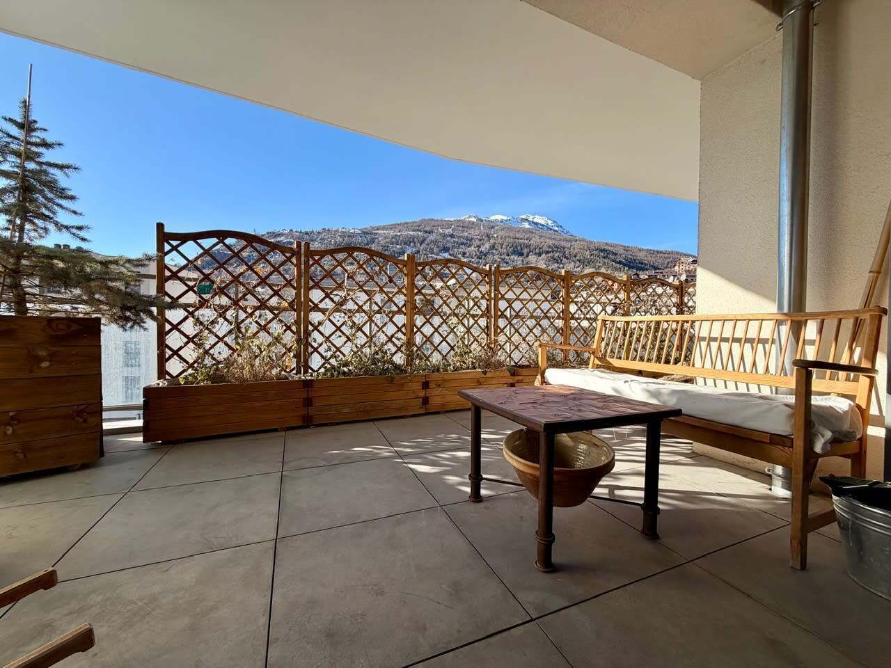An outdoor patio with a wooden bench, a table, and a woven basket.