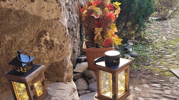 Two wooden lanterns on a stone ledge, a potted plant with autumn leaves, and a stone wall. - Maison Cavalese - Polar Express - Intimacy in the center of town (Cavalese)