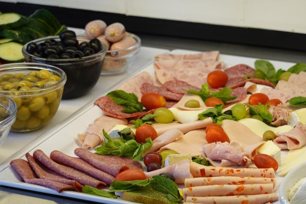 A charcuterie board with various meats, cheeses, olives, and vegetables.