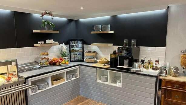 Eine moderne Küche mit grauer Ziegelrückwand, Holzarbeitsplatten und einer Kaffeestation.