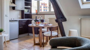 Une cuisine moderne avec des meubles de couleur sombre, un réfrigérateur blanc et un coin repas comprenant une table ronde et quatre chaises.
