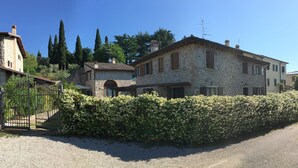 A stone building with a large arched entrance, a gravel driveway, and a hedge in front. - Ca' Malfer B&B (Marciaga)