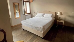A bedroom with a wooden ceiling, a bed, a nightstand, a chair, and a window. - Ca' Malfer B&B (Marciaga)
