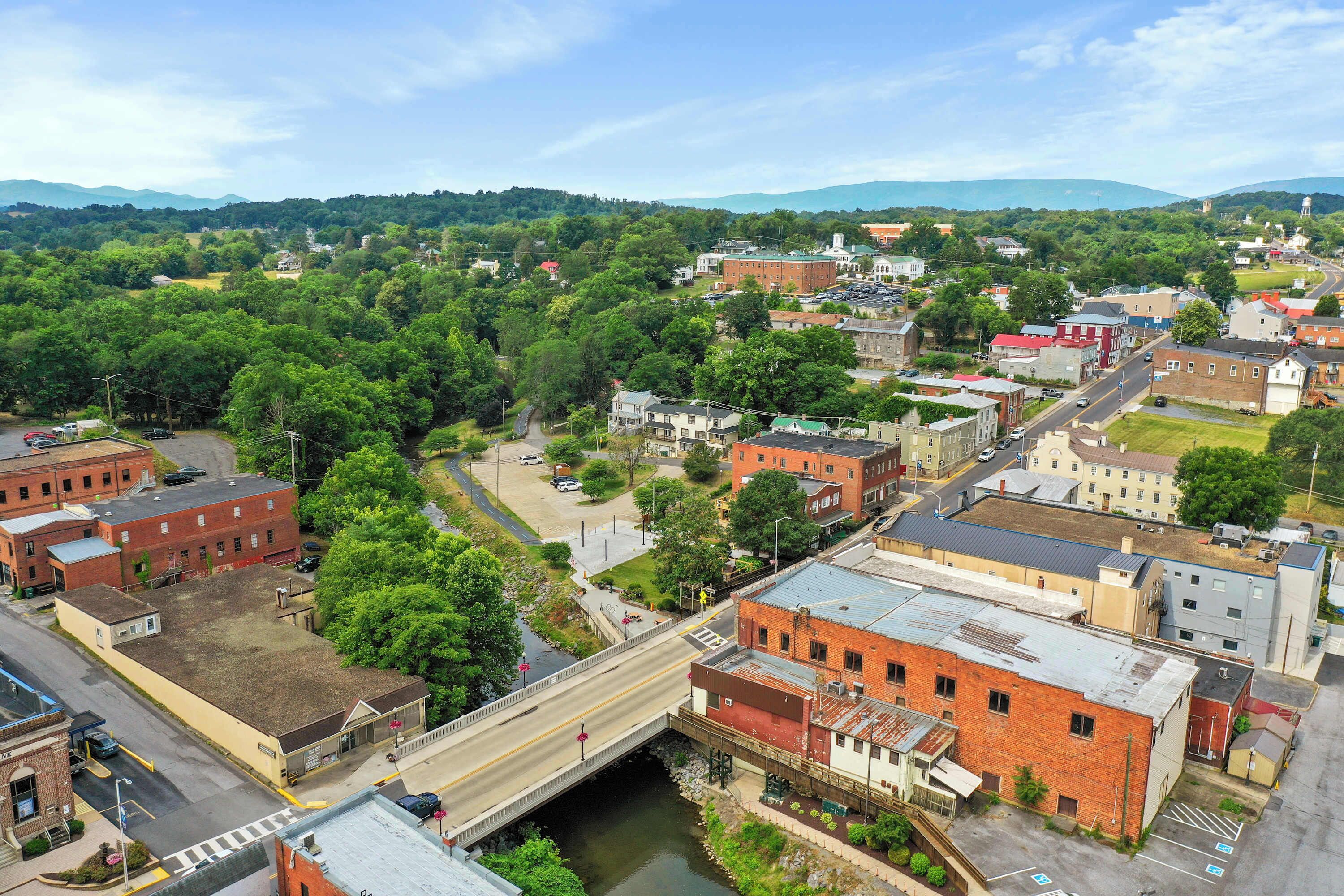 An aerial view of a town with a river running through it, surrounded by greenery and buildings.