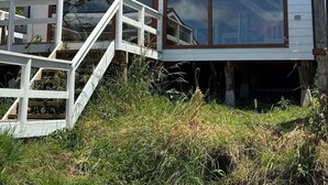 Un edificio blanco con amplios ventanales y una escalera que sube a una terraza.