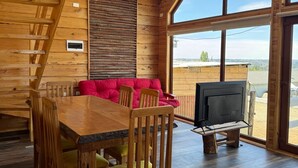 Interior de madera con una mesa de comedor, sillas, un sofá rojo y un televisor.